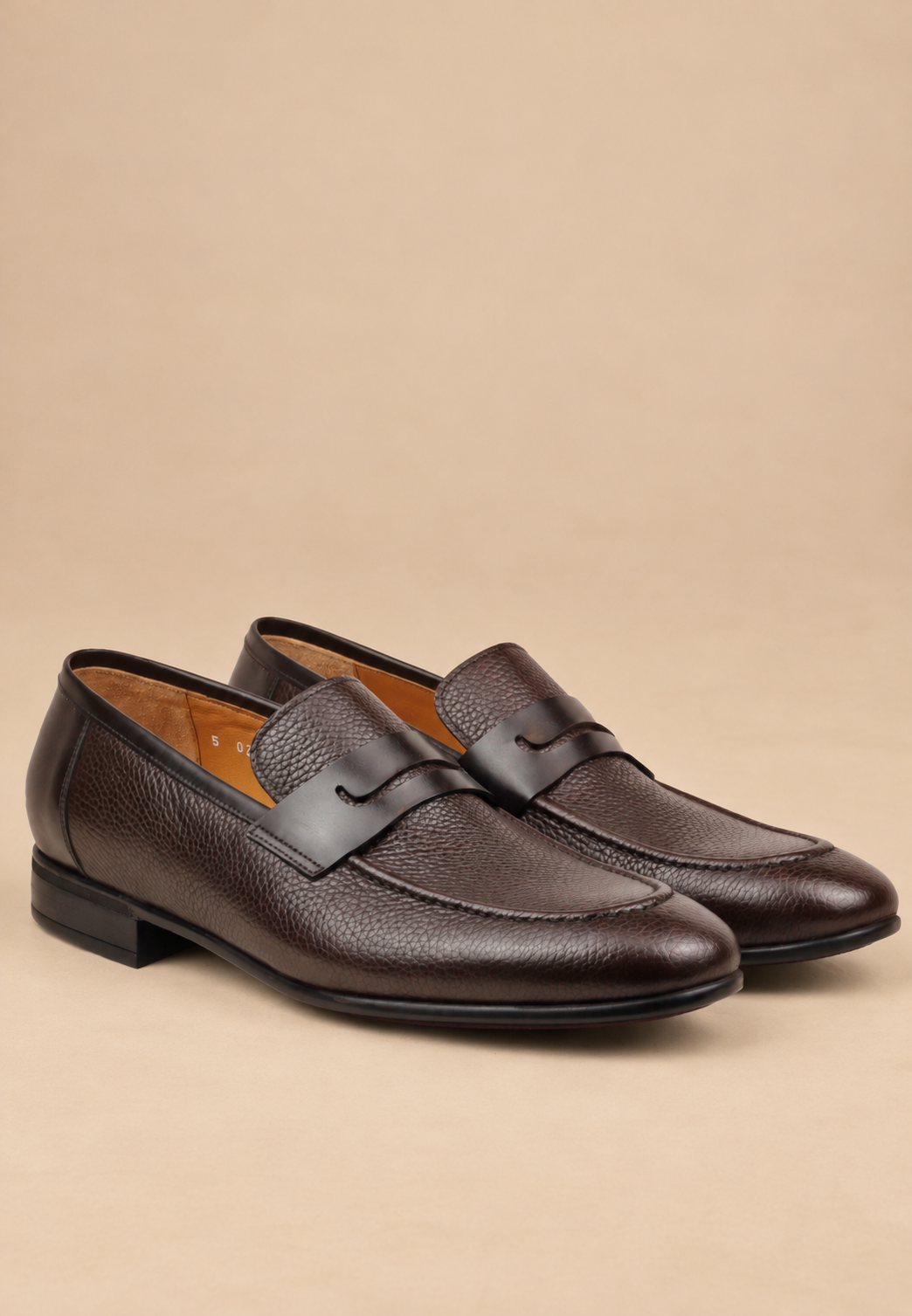 Lusso Brown pebbled leather loafers on a warm beige background
